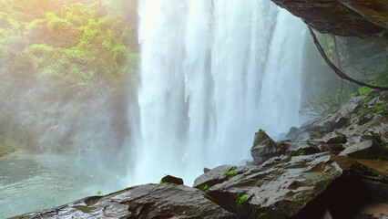 Serene cave sanctuary: Waterfall's embrace amid lush tropical paradise, nature's hidden gem. Huai...