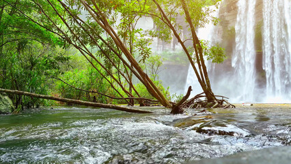 Spectacular waterfall cascading from towering cliff, enveloped by vibrant tropical greenery, a...