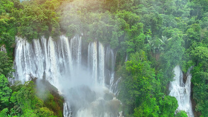 The drone reveals nature's hidden masterpiece - an awe-inspiring waterfall nestled deep within the vibrant tapestry of the tropical jungle, a verdant haven of serenity. Lush woods: Nature's haven.
