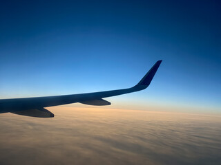 View from airplane window. Airplane wing in the blue sky above the clouds. 