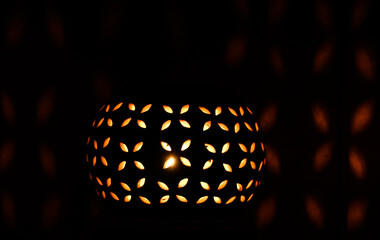 Burning candle in the shape of a flower pumpkin on a black background. Beautiful pattern