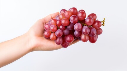 a hand holding a bunch of ripe red grapes, highlighting their plumpness and freshness against a white backdrop.