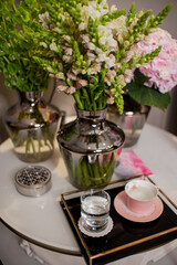 bouquets of flowers are on the table, a tray with a cup and a glass of water
