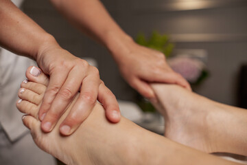 Massage therapist doing foot and leg massage with hands