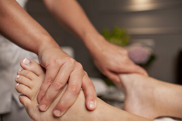 Massage therapist doing foot and leg massage with hands