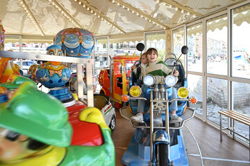 two children playing on a motorcycle in a merry-go-round