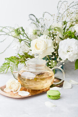 Aesthetic table setting. Green tea teapot, macaroon desserts, white roses and eustomas. Time for yourself, rest, core, slow living concept.