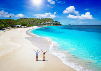 Elevated view of a happy couple standing on a tropical paradise beach with turquoise sea in the...