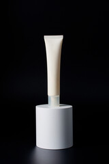 Plastic white tube for cream or lotion. Skin care or sunscreen cosmetic with stylish props on black background.