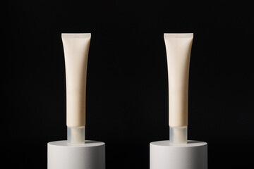 Plastic white tube for cream or lotion. Skin care or sunscreen cosmetic with stylish props on black background.
