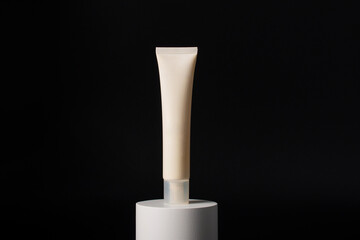 Plastic white tube for cream or lotion. Skin care or sunscreen cosmetic with stylish props on black...