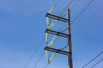 Electric pole made of concrete with aluminum wires on the background of blue sky from bottom to top.