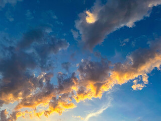 Stunning capture of sunset clouds painted with golden edges against a deep blue sky, perfect for illustrating majestic and tranquil scenes