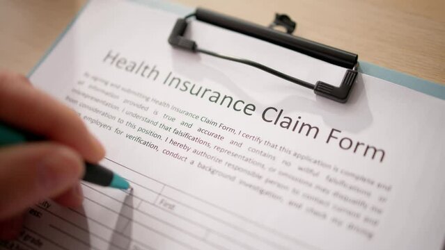 Close-up Of Hand Holding Pen Over Medical Claim Application