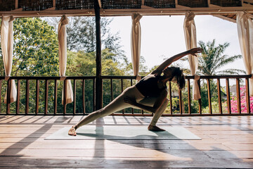 Full length of woman practicing yoga on exercise mat at wellness resort