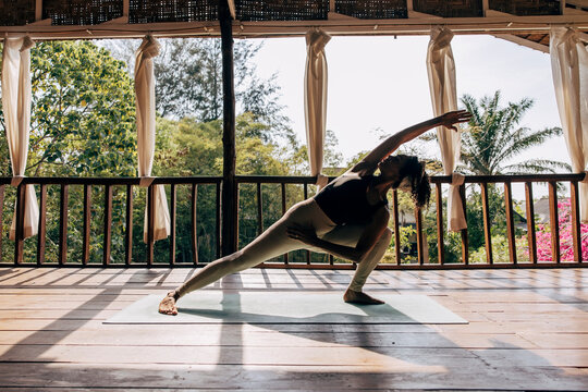 Full length of woman practicing yoga on exercise mat at wellness resort