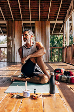 Mature man practicing Matsyendrasana pose while sitting on yoga mat at wellness resort