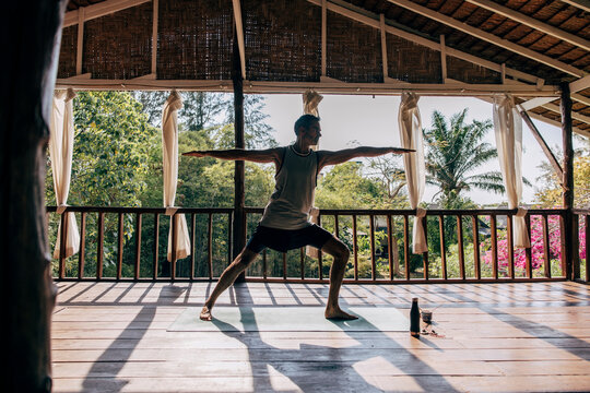 Mature man practicing Warrior 2 pose while exercising at wellness resort