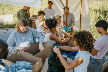 High angle view of volunteers team sorting clothes from cardboard boxes during charity drive at community center