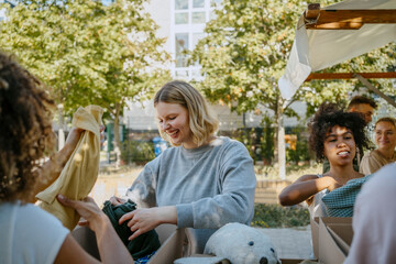 Happy volunteer helping team while sorting out clothes during charity drive at community center
