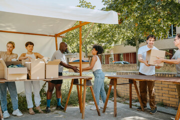 Group of male and female volunteers passing boxes during charity drive at community center