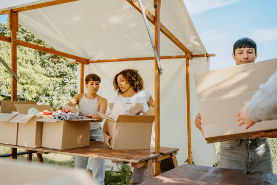 Female volunteers arranging boxes with donation goods on table during charity drive at community center