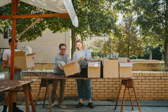 Group of multiracial volunteers arranging cardboard boxes on table during charity drive at community center