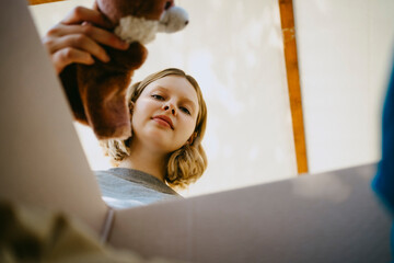 Low angle portrait of young volunteer removing teddy bear from box during charity drive at community center