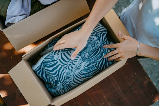 Directly above view of male volunteer packing blanket in box on table at community center