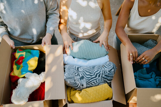 Midsection of multiracial volunteers with boxes of donation goods at community center