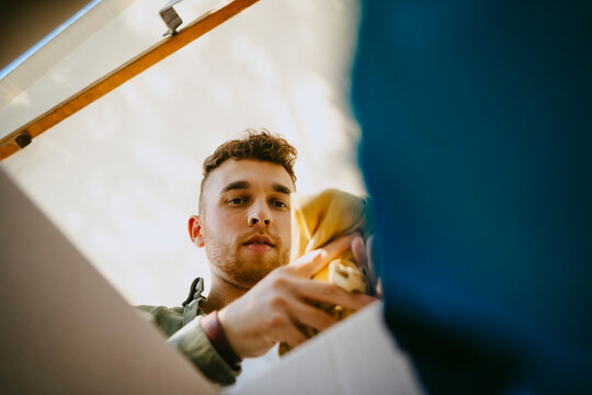 Low angle view of male volunteer removing clothes from box during charity drive at community center