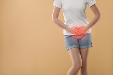 Woman suffering from cystitis symptoms on beige background, closeup. Space for text