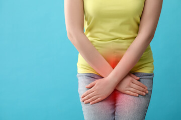 Woman suffering from cystitis symptoms on light blue background, closeup