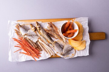 Various fish snacks and dried fruits on wooden table