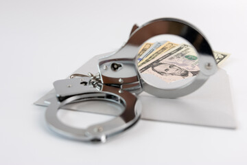 Handcuffs, dollars and an envelope. The concept of financial dependence.