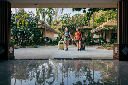 Full length of male and female tourists arriving with luggage at resort