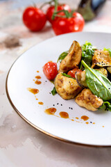 Fresh salad with grilled vegetables, greens, and tomatoes on a white plate
