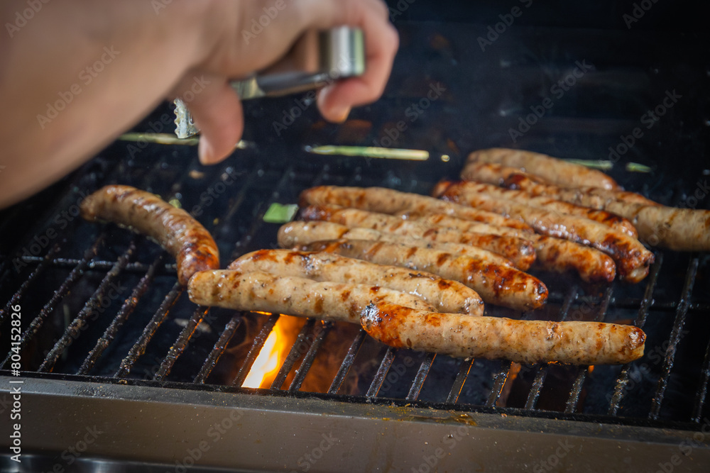 Canvas Prints saucisses en cuisson sur une grille de barbecue, avec des flammes attisées par la graisse.