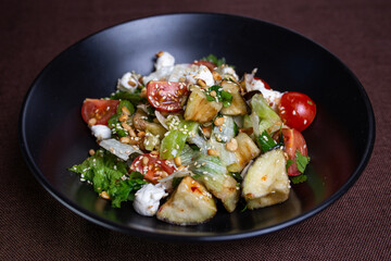 Delicious salad with fresh vegetables and feta cheese on black plate