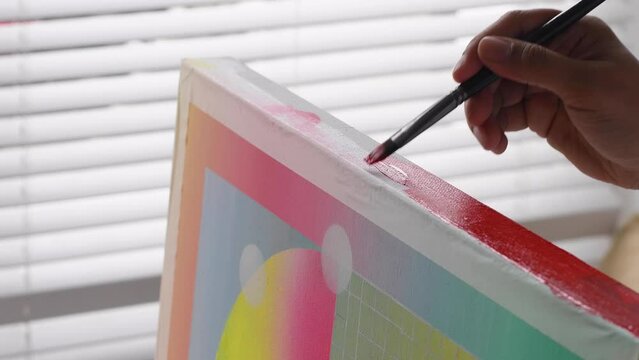A diverse biracial female artist, painting the edge of a canvas in bright orange. The canvas has soft pastel gradient background with geometric shapes