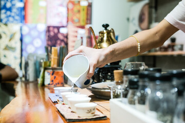 A tea master in a Glodok teahouse, Jakarta’s Chinatown, elegantly pours tea from a golden teapot, creating a warm and authentic atmosphere rich in Chinese tea culture and tradition.