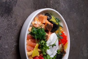Scrumptious seafood rice bowl with fresh vegetables and egg on a dark background