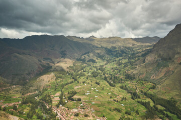 Vast green valley with mountain ranges and small town in Peru