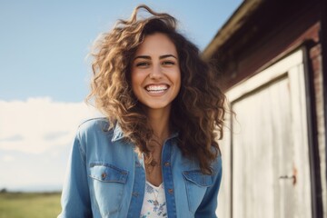 Fototapeta premium Portrait of a cheerful woman in her 20s sporting a versatile denim shirt in front of quiet countryside landscape