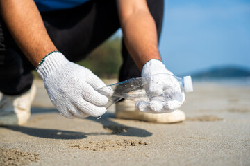Close up hand pick up the plastic bottle on the beach. People male and female Volunteer with...