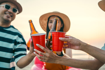 Happy friends cheering and drinking cheering beer at beach party outdoor. people vacation holiday...