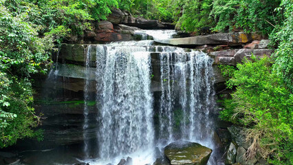 Breathtaking drone view of a majestic tropical waterfall cascading from a towering cliff in a lush...