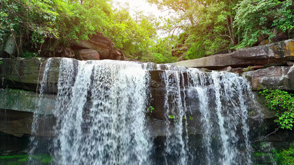 Drone captures breathtaking tropical waterfall cascading from towering cliff in lush forest. Thung Na Muang Waterfall, Pha Taem National Park, Ubon Ratchathani Province, Thailand. Travel concept.
