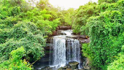 A breathtaking drone view of an epic, lush forest paradise with a stunning waterfall cascading...