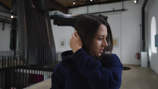 Frustrated female brunette fix hair at art gallery David Cerny, Prague